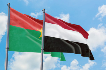 Yemen and Burkina Faso flags waving in the wind against white cloudy blue sky together. Diplomacy concept, international relations.