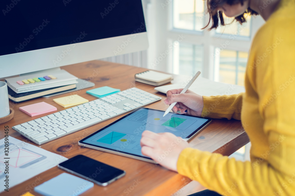 Wall mural designer woman drawing a website outline and website ux app development on mobile phone.