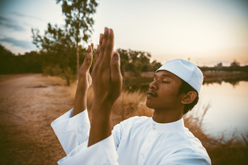 Silhouette Young asian muslim man praying on sunset,Ramadan festival concept