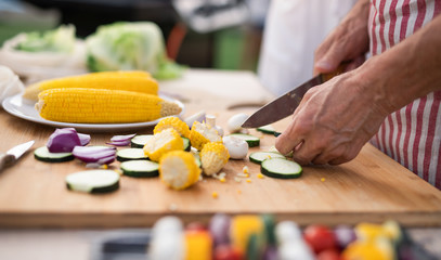 Midsection of family outdoors on garden barbecue, grilling.