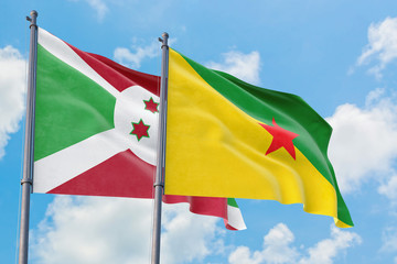 French Guiana and Burundi flags waving in the wind against white cloudy blue sky together. Diplomacy concept, international relations.