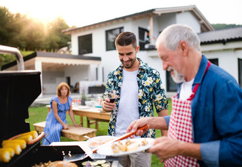 Portrait of multigeneration family outdoors on garden barbecue, grilling.