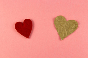 crumpled paper in the shape of two hearts, small and large, on a pink background from natural paper. Copyspace for text