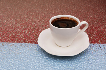 Close-up - a cup of coffee on a red-blue background.