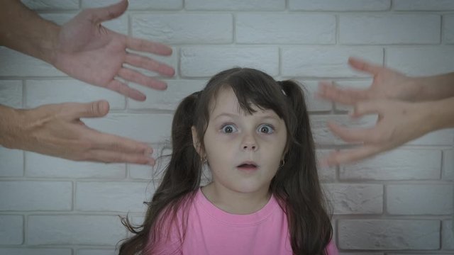 Parents stress for child. The little girl is shocked by the fact that her parents are yelling at her.