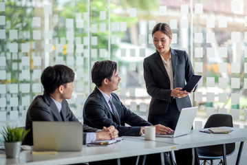 Young asian businesswoman presenting to colleagues and discussing about the project at meeting.