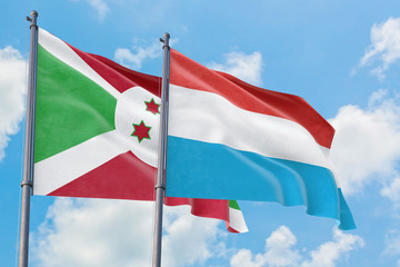 Luxembourg and Burundi flags waving in the wind against white cloudy blue sky together. Diplomacy concept, international relations.