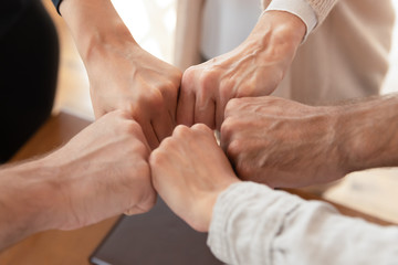 Fototapeta premium Close up of diverse employees join fists engaged in teambuilding