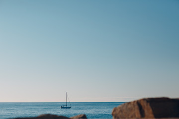 The yacht is sailing along the sea, the coast with large stones
