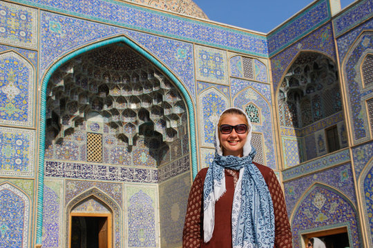 Young girl tourist on the background of the famous Jameh Mosque of Isfahan. Great heritage of Persian architecture, blue mosaic