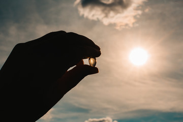 Hand holding fish oil vitamin d transparent capsules. Dietary supplements