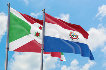 Paraguay and Burundi flags waving in the wind against white cloudy blue sky together. Diplomacy concept, international relations.