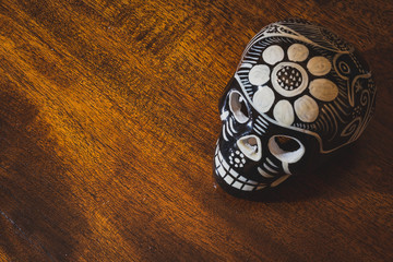 Calavera mexicana negra y blanca, sobre madera marrón con taras oscuras