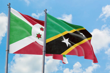 Saint Kitts And Nevis and Burundi flags waving in the wind against white cloudy blue sky together. Diplomacy concept, international relations.