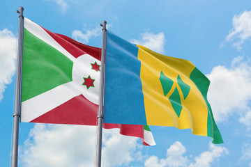 Saint Vincent And The Grenadines and Burundi flags waving in the wind against white cloudy blue sky together. Diplomacy concept, international relations.