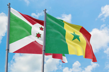 Senegal and Burundi flags waving in the wind against white cloudy blue sky together. Diplomacy concept, international relations.