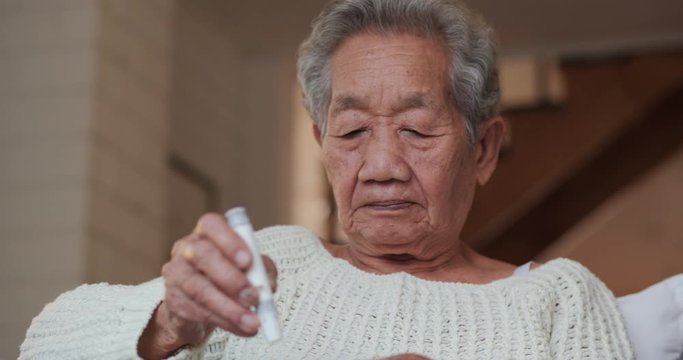 Asian Senior Woman using Medical Equipment to Check Her Blood at Home. Healthcare and Medical Concept.
