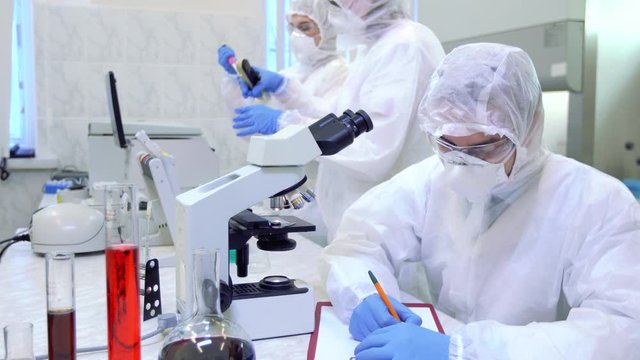 Scientists in protective suits in a science laboratory study a dangerous virus to eliminate the epidemic.