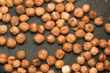 Peeled hazelnuts in a cast-iron pan top view, close-up