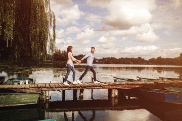 Happy young couple outdoors. young love couple running along a wooden bridge holding hands.