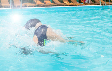 Two female swimmers simultaneously dive in an outdoor pool, demonstrating their skill, Sunny summer...