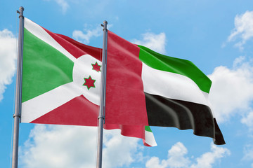 United Arab Emirates and Burundi flags waving in the wind against white cloudy blue sky together. Diplomacy concept, international relations.