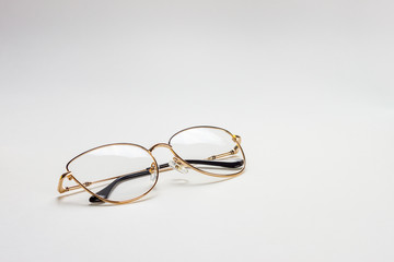 The perspective view of a golden female medical eyeglasses with folded temples on a white background