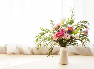 Beautiful delicate flower bouquet with roses, eustomas and eucalyptus leaves in a vase on a windowsill