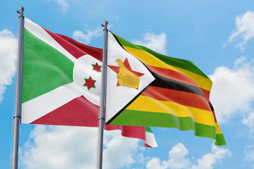 Zimbabwe and Burundi flags waving in the wind against white cloudy blue sky together. Diplomacy concept, international relations.
