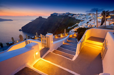 Naklejka premium Miasto Fira na wyspie Santorini, Grecja. Niezwykle romantyczny zachód słońca na Santorini. Wioska Oia w świetle poranka. Niesamowity widok zachodu słońca z białymi domami. Miłośnicy wysp