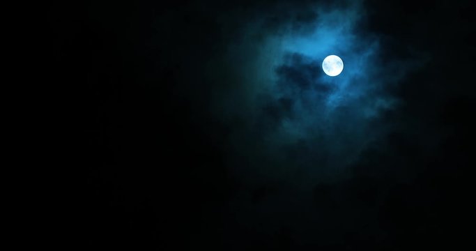 Full moon on dark cloudy night. Clouds passing by the moon in spooky feeling like thriller and horror films.