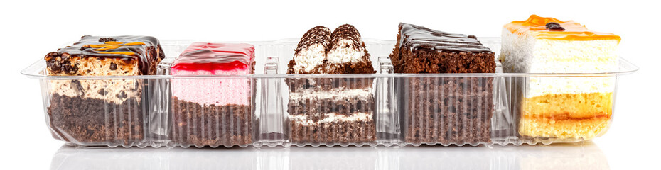Assorted Tiramisu cakes in an open transparent plastic box isolated on white background. Front view