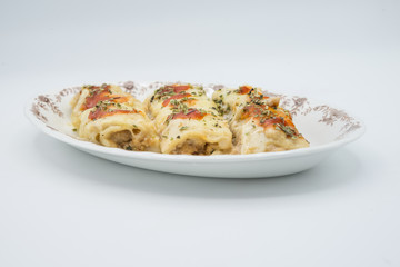 Canelones (cannelloni) with meat filled pasta and cheese and tomato on a plate