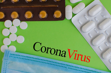 Text phrase Coronavirus on a green background with medicines and protective masks. Novel...