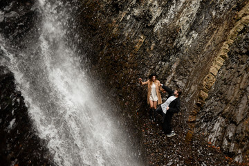 Fototapeta na wymiar Beautiful couple in love walks near a waterfall, hiking and an active lifestyle. Holidays in Norway and the Scandinavian countries
