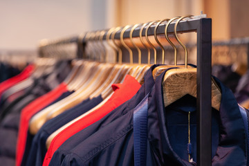 Fototapeta premium Closeup colorful male, female clothes in boutique hanging on hangers, clothing rack on metal stand. Concept opening luxury shop, shopping mall, store sale, retail fashion store, second hand outlet.