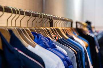 Closeup colorful male, female clothes in boutique hanging on hangers, clothing rack on metal stand....