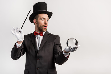 shocked magician holding wand and magic ball, isolated on grey - obrazy, fototapety, plakaty