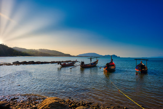 Small wooden fisherman boads on water sea witn sun ray and clear sky. With copy space for text or design.