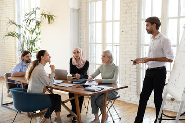 Male coach making flip chart presentation for multiracial colleagues