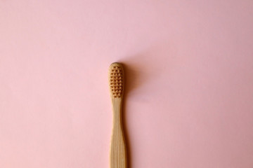 Bamboo toothbrush on pale pink background. Zero waste lifestyle concept. Flat lay.