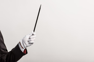partial view of magician in glove holding wand, isolated on grey