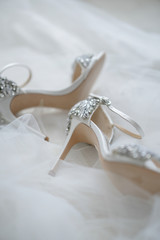 White shoes of the bride in brilliant crystals lie on the veil. Things for an elegant wedding.