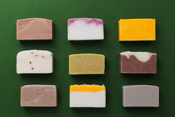 Flat lay composition with handmade soap bars on dark green background, top view