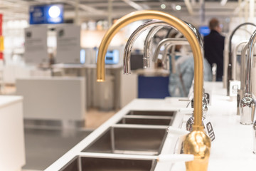 Blurry customer shopping for kitchen faucets at furniture showroom store in Texas, USA