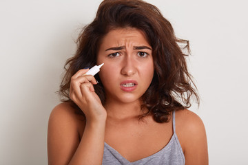 Closeup portrait of sad serious young woman with disappointed facial expression, posing isolated over white background, looking at camera with upset facial expression, having problems with skin.