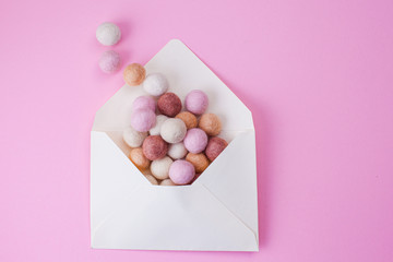 Colorful handmade felt balls fly out of paper envelope. Message, mail and letter concept