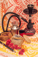 Still life consisting of hookah, flowers, figs, cinnamon, candles and tea-making utensils