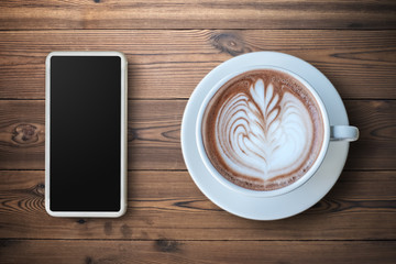 Smartphone with a cup of Espresso coffee with beautiful latte art on wooden background.
