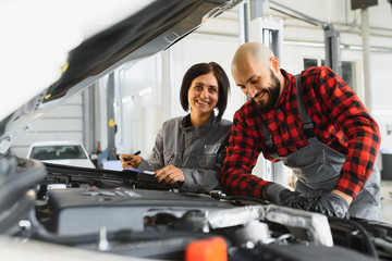 Male and female mechanics working on car